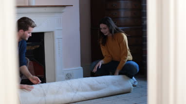 Couple rolling out rug in new home