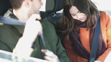 Couple putting seat belts on ready for drive