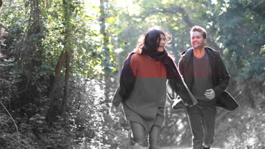 Couple running in forest in Fall