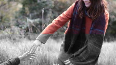 Girlfriend helping boyfriend up in countryside