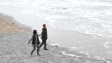 Couple walking on beach in Winter