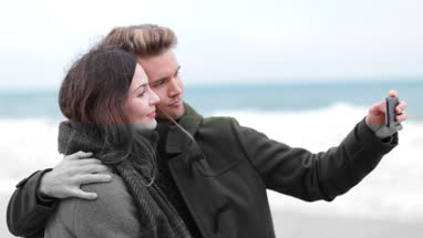 Couple taking selfie on beach in Winter