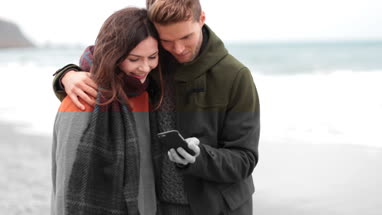 Couple reviewing selfie on beach in Winter