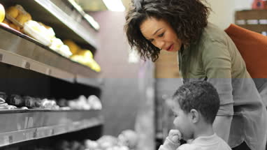 Mother and son buying fruit and vegetables in grocery store