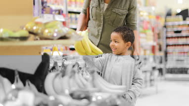 Boy picking up bananas in grocery store