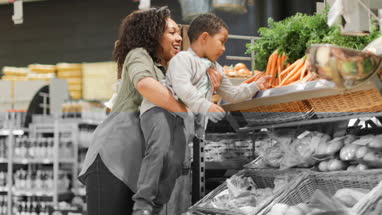 Boy picking up carrots in grocery store