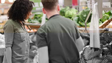 Shop assistant in grocery store helping shoppers