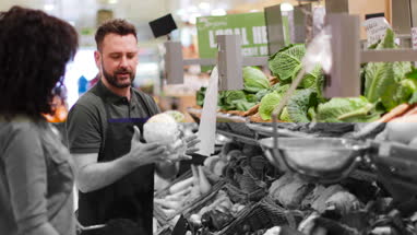 Shop assistant in grocery store helping shoppers