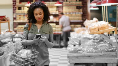 Woman grocery shopping and using smartphone