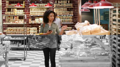 Woman grocery shopping and using smartphone
