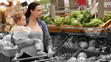 Mother and daughter buying vegetables in grocery store