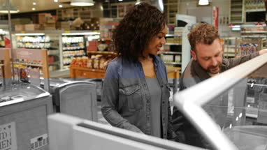 Couple looking at ready meal in grocery store