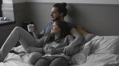 Young couple having coffee in bed