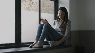 Young adult female having morning coffee and checking smartphone