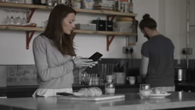 Young couple looking at smartphone together over breakfast