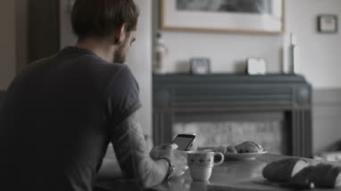 Over shoulder shot of young adult male using smartphone