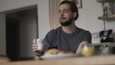 Young adult male having morning coffee and checking smartphone
