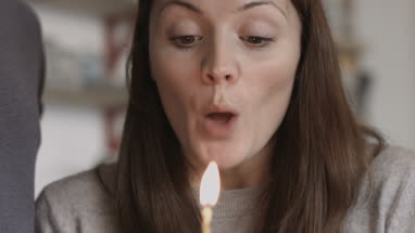Young adult female blowing out candle on cupcake