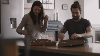 Young couple eating takeout pizza at home