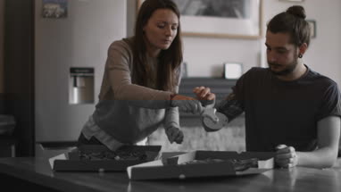 Young couple eating takeout pizza at home