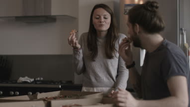 Young couple eating takeout pizza at home