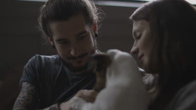 Young couple giving treat to pet puppy Jack Russell
