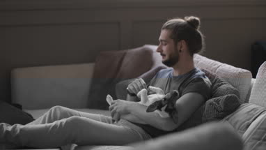 Young adult male watching TV with pet puppy