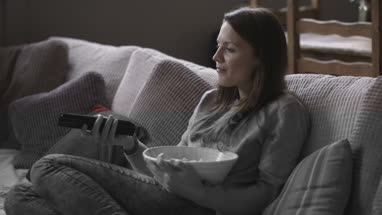 Young adult female eating popcorn and watching home movie