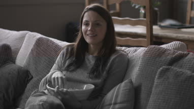 Young adult female eating popcorn and watching home movie