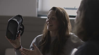 Young adult female taking off VR headset 