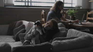 Young female cuddling puppy at home