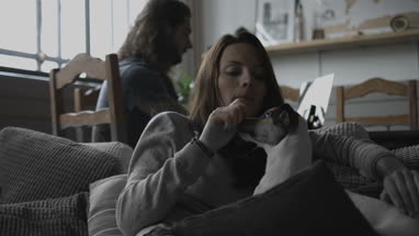 Young female cuddling puppy at home