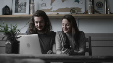 Young adult couple using a laptop and smartphone together
