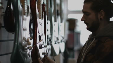 Young adult male looking at guitar in shop