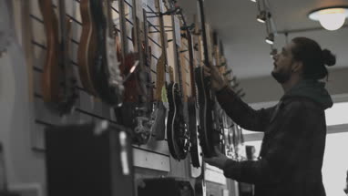 Young adult male looking at guitar in shop