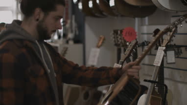 Young adult male looking at guitar in shop