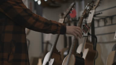 Young adult male looking at guitar in shop