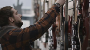 Young adult male pricing guitar in shop