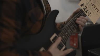 Young adult male picking guitar in shop