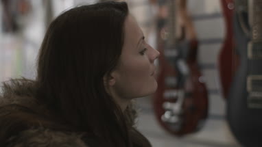 Young adult female looking at guitar in shop