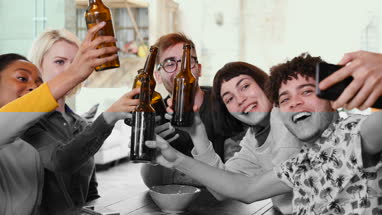 Group of friends posing for a group selfie with beer bottles