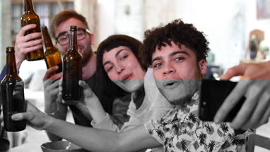 Group of friends posing for a group selfie with beer bottles