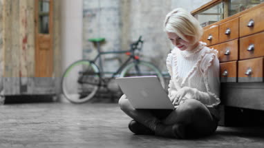 Young adult female sitting on floor working on laptop