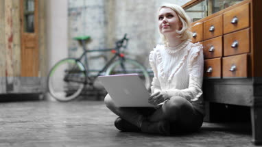 Young adult female sitting on floor working on laptop