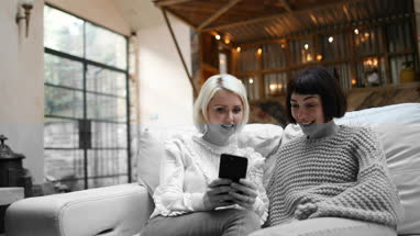 Young adult female friends looking at smartphone at home