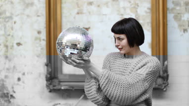 Young adult female looking at her reflection in disco ball