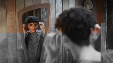 Young adult male grooming hair looking in mirror