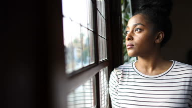Young adult female looking out of the window thinking