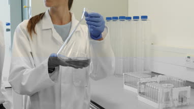 Female scientist analyzing liquid in conical flask with a male colleague