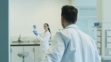 Female scientist analyzing liquid in conical flask with a male colleague